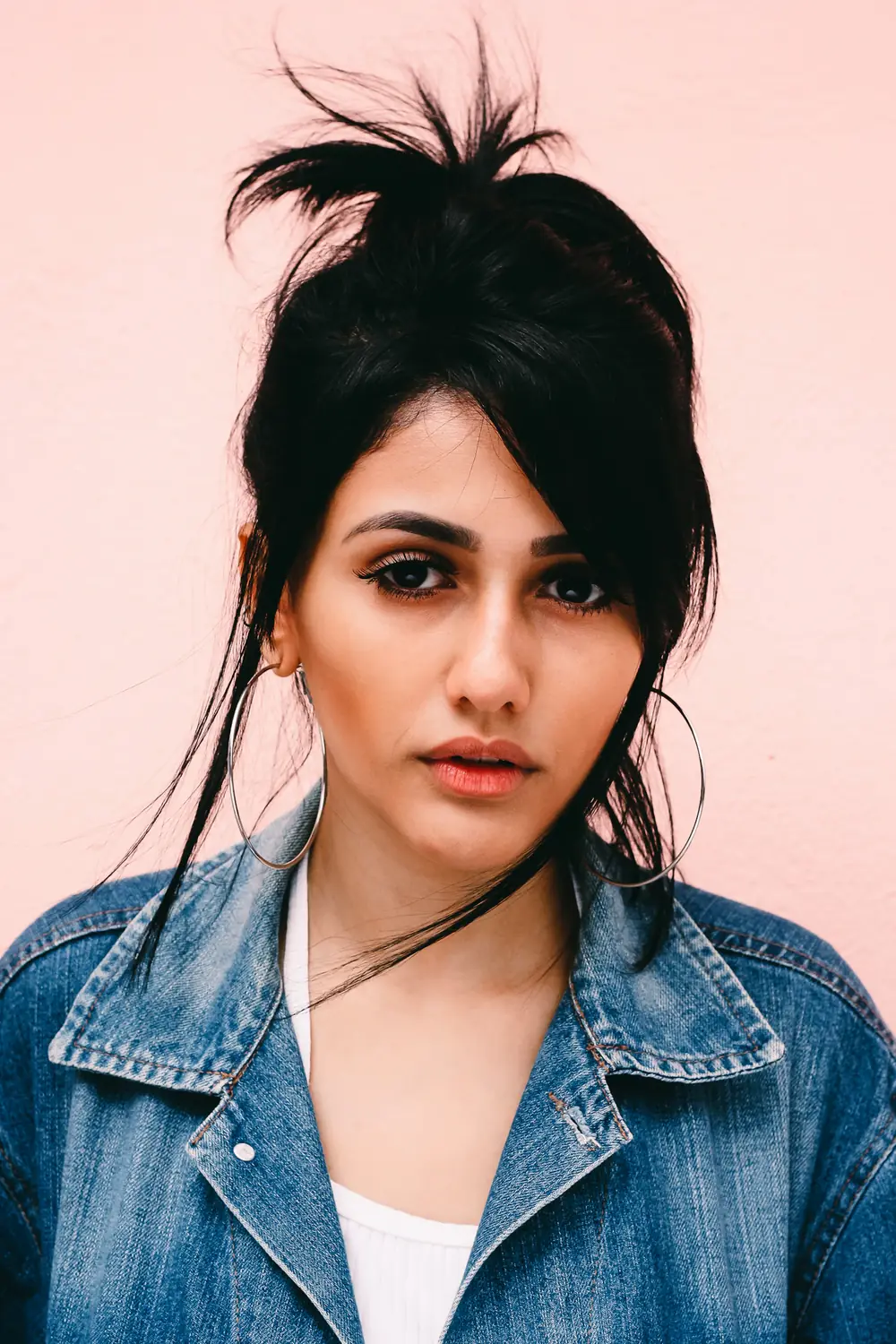 Portrait against a pale wall, hoop earrings